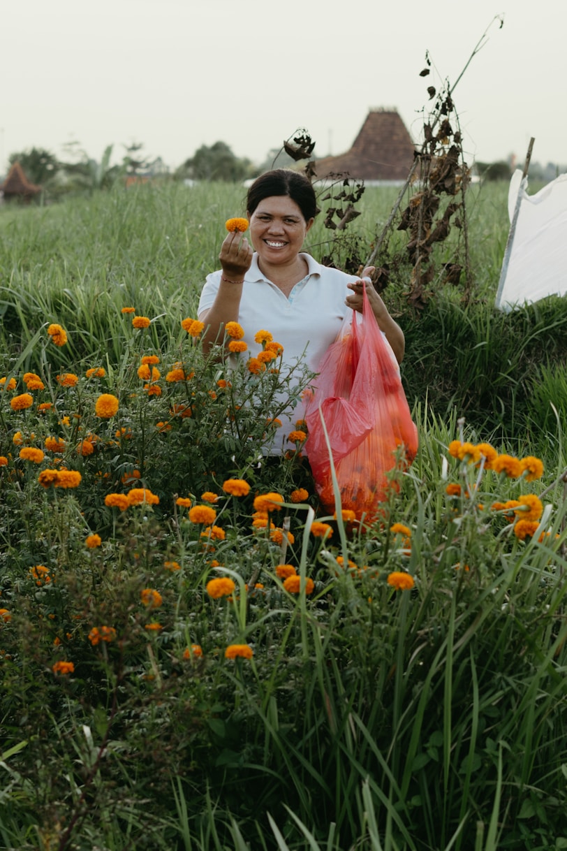 A woman in a field of flowers holding a bag