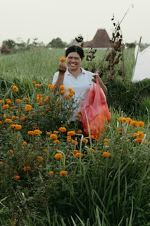 A woman in a field of flowers holding a bag