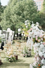 A wedding ceremony in a park with white and pink flowers