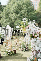 A wedding ceremony in a park with white and pink flowers