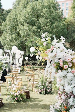 A wedding ceremony in a park with white and pink flowers