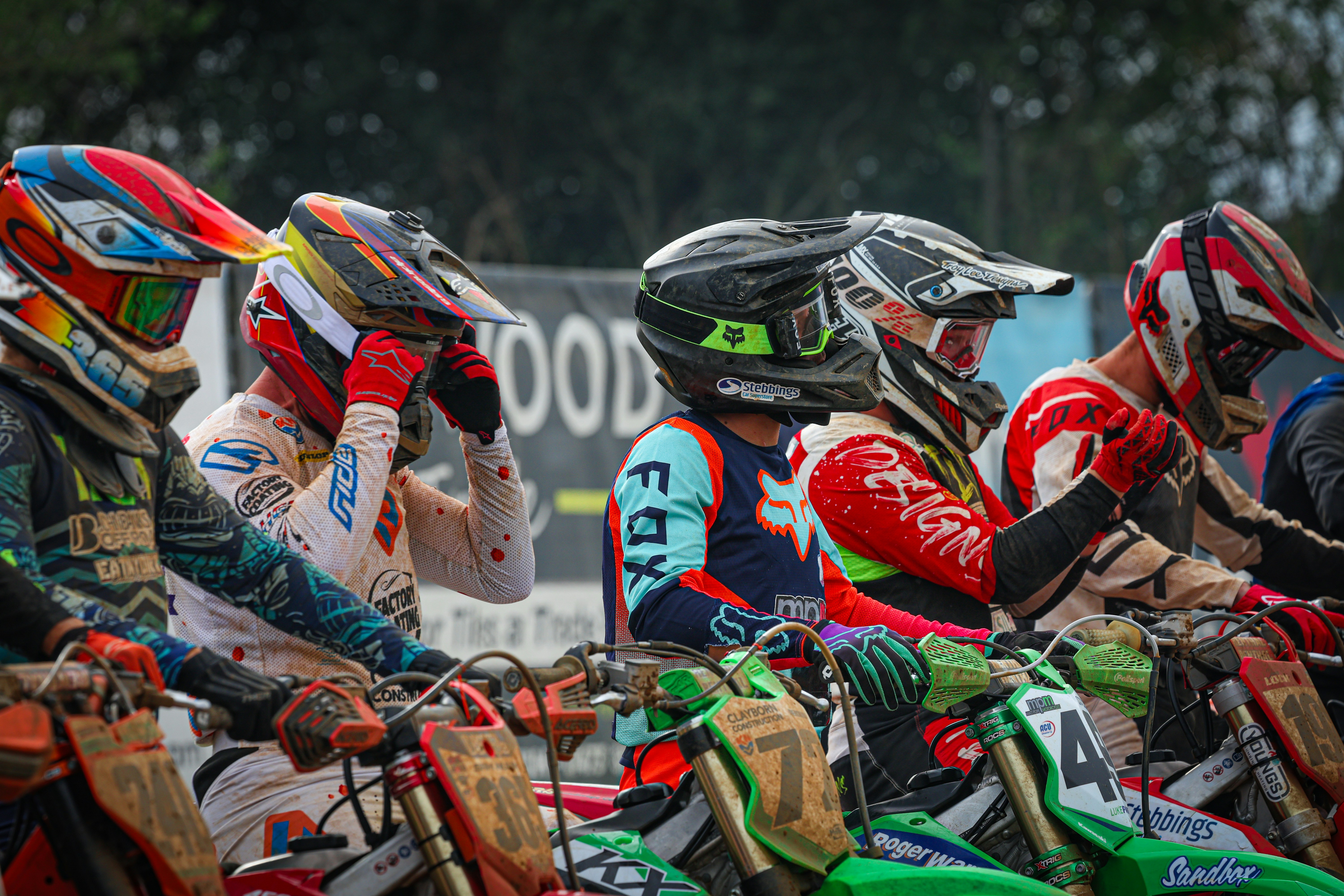 A group of dirt bike riders sitting next to each other