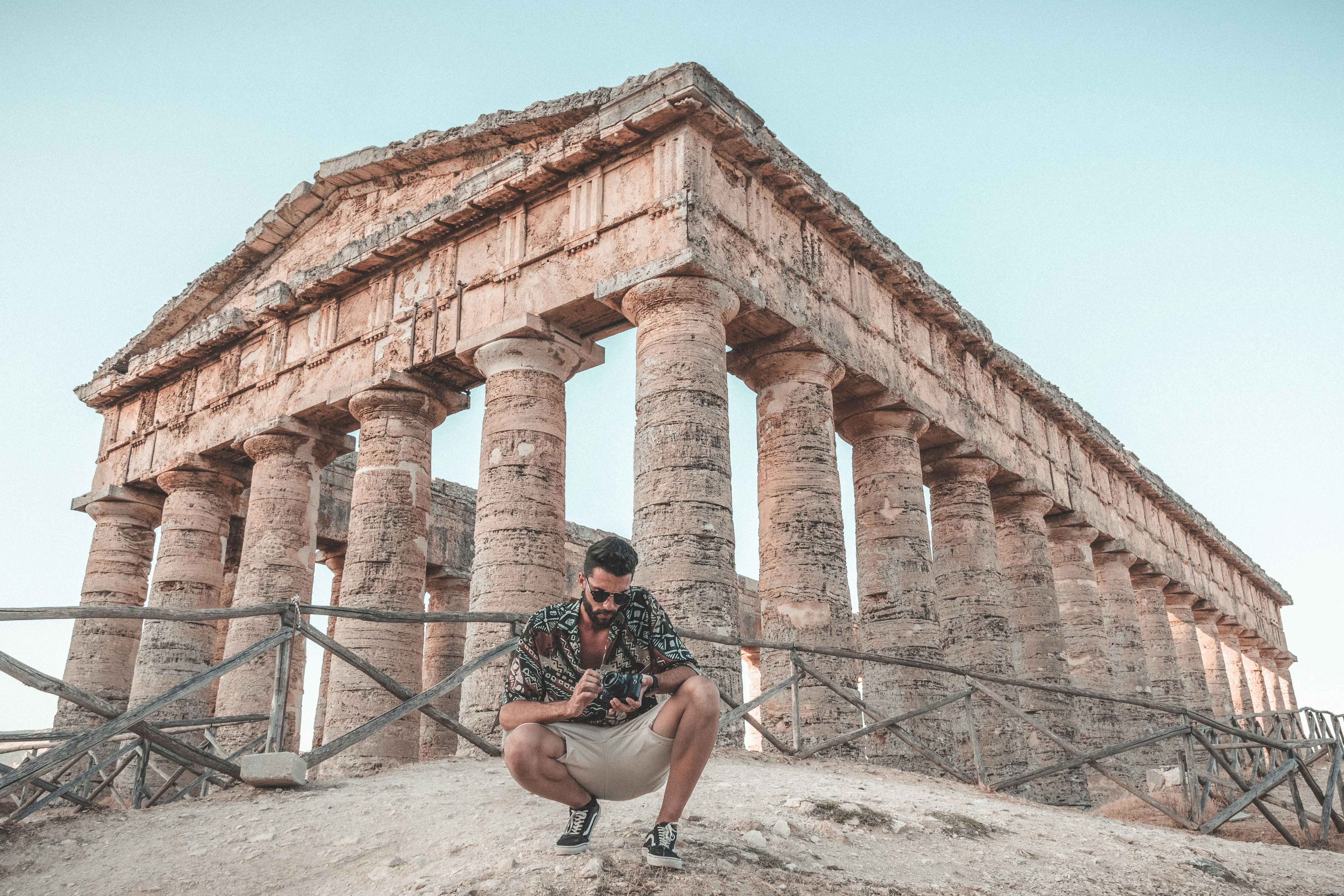A man kneeling down in front of a stone structure