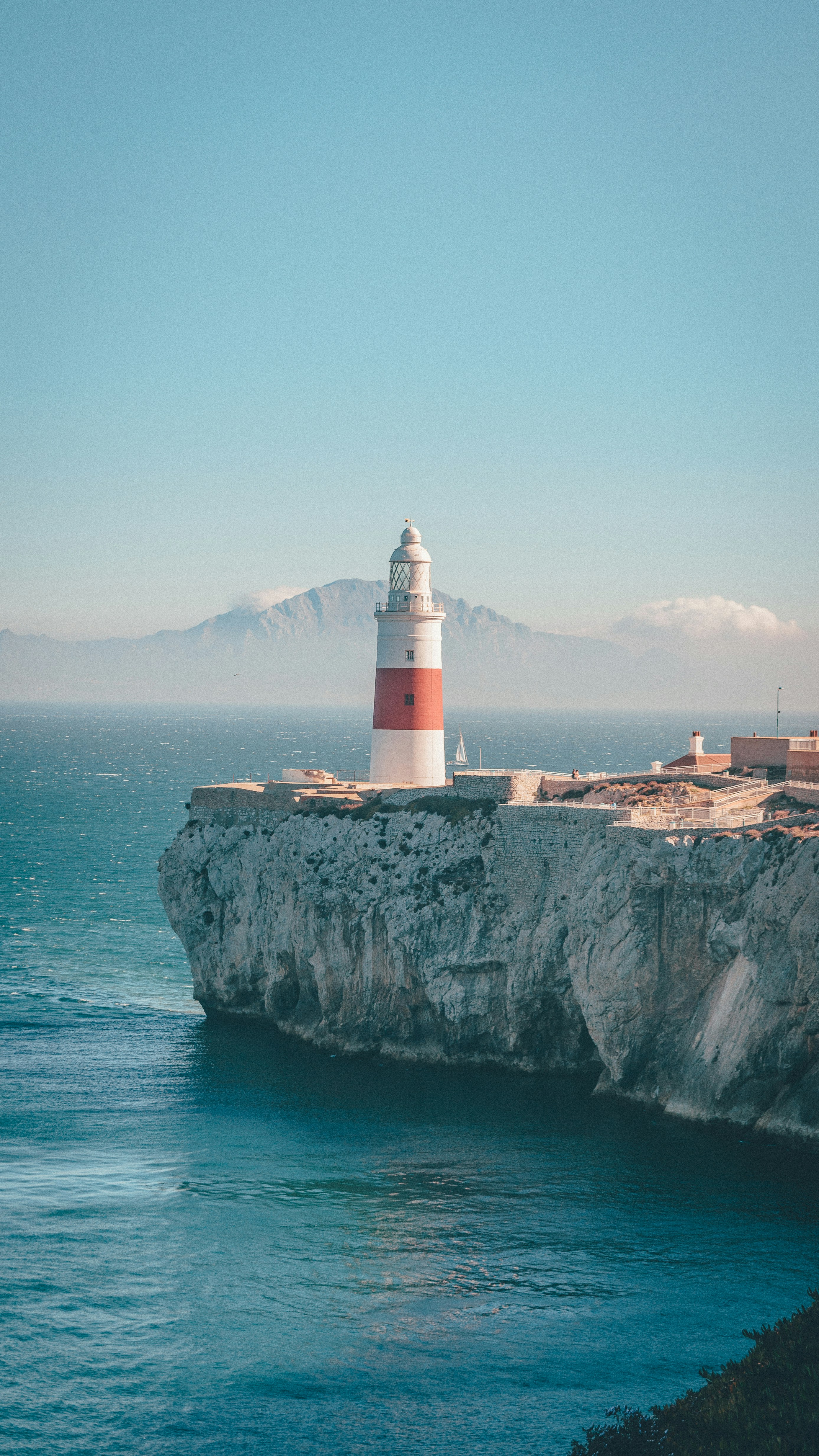 A red and white lighthouse sitting on top of a cliff next to the ocean