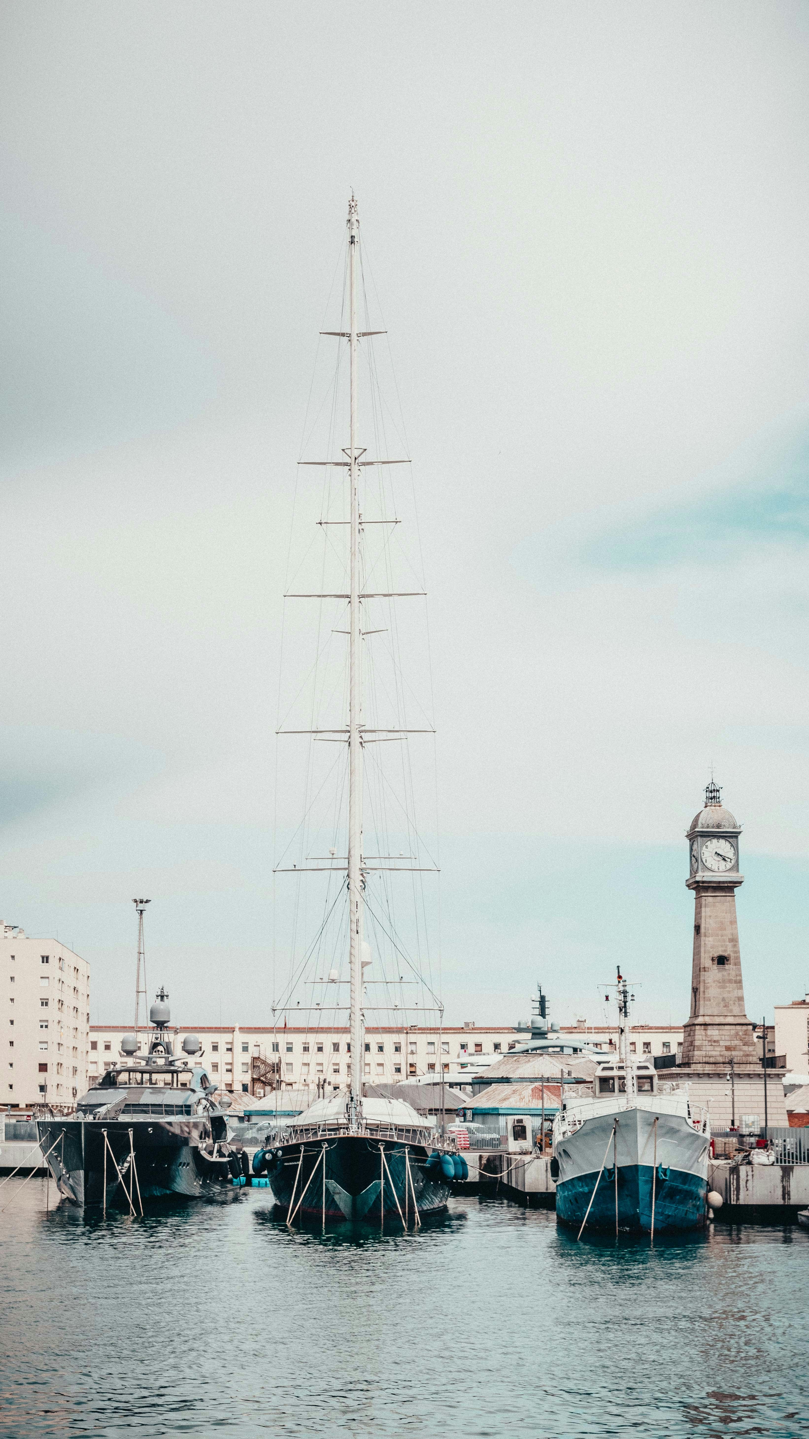 A sailboat docked in a harbor with a lighthouse in the background