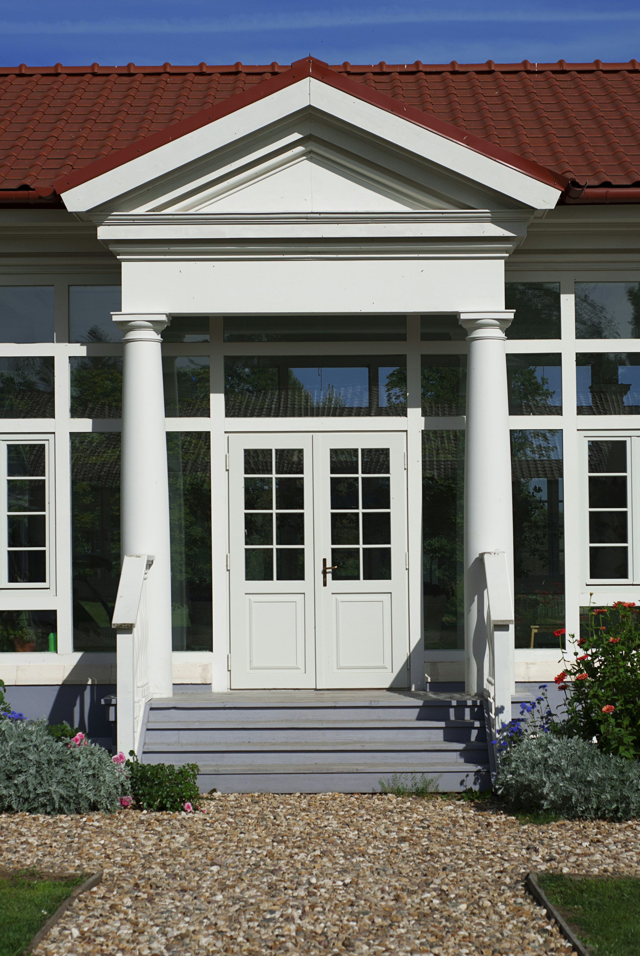 Una casa bianca con tetto rosso e colonne bianche