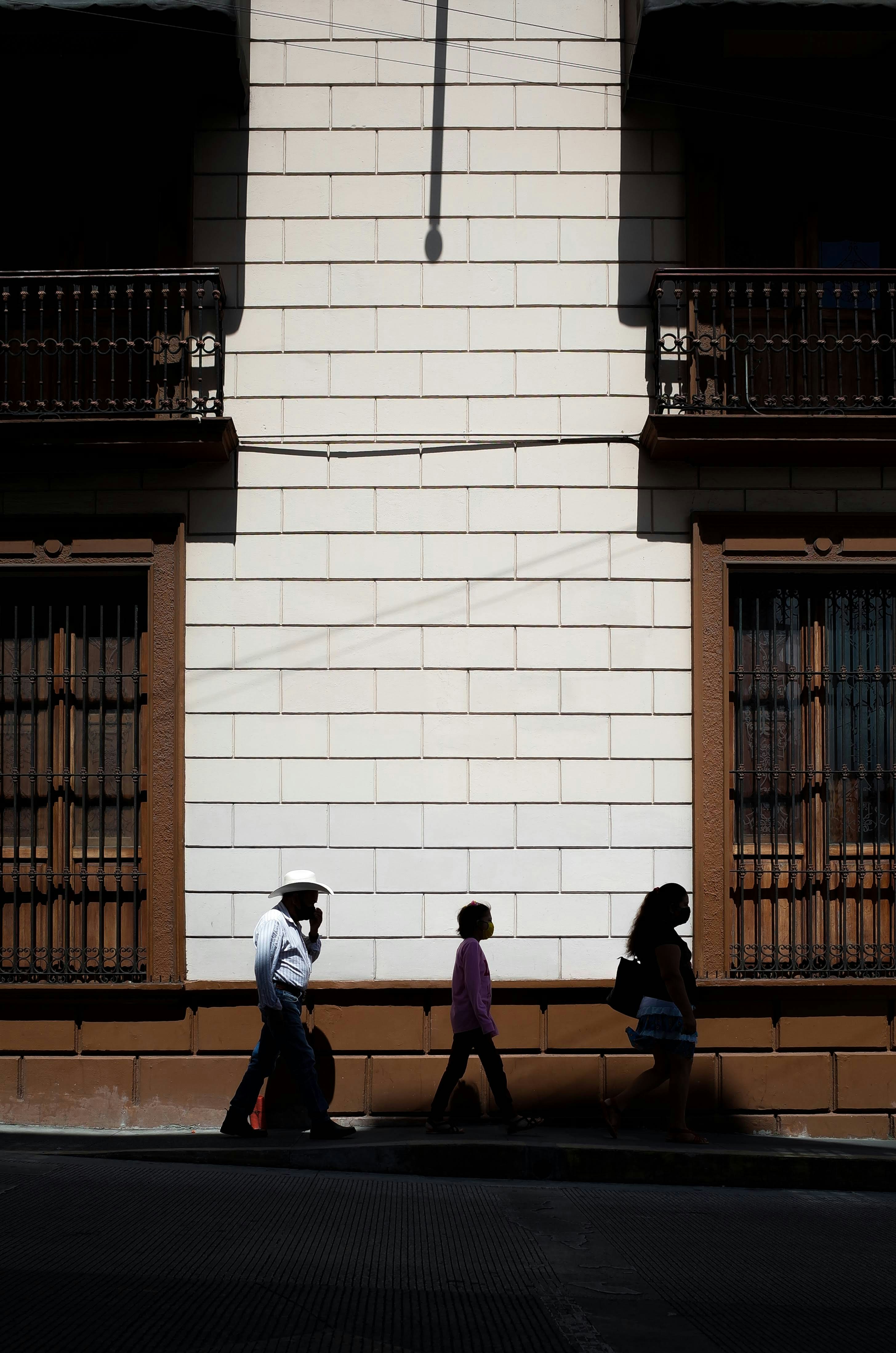 Eine Gruppe von Menschen, die eine Straße neben einem hohen Gebäude entlanggehen