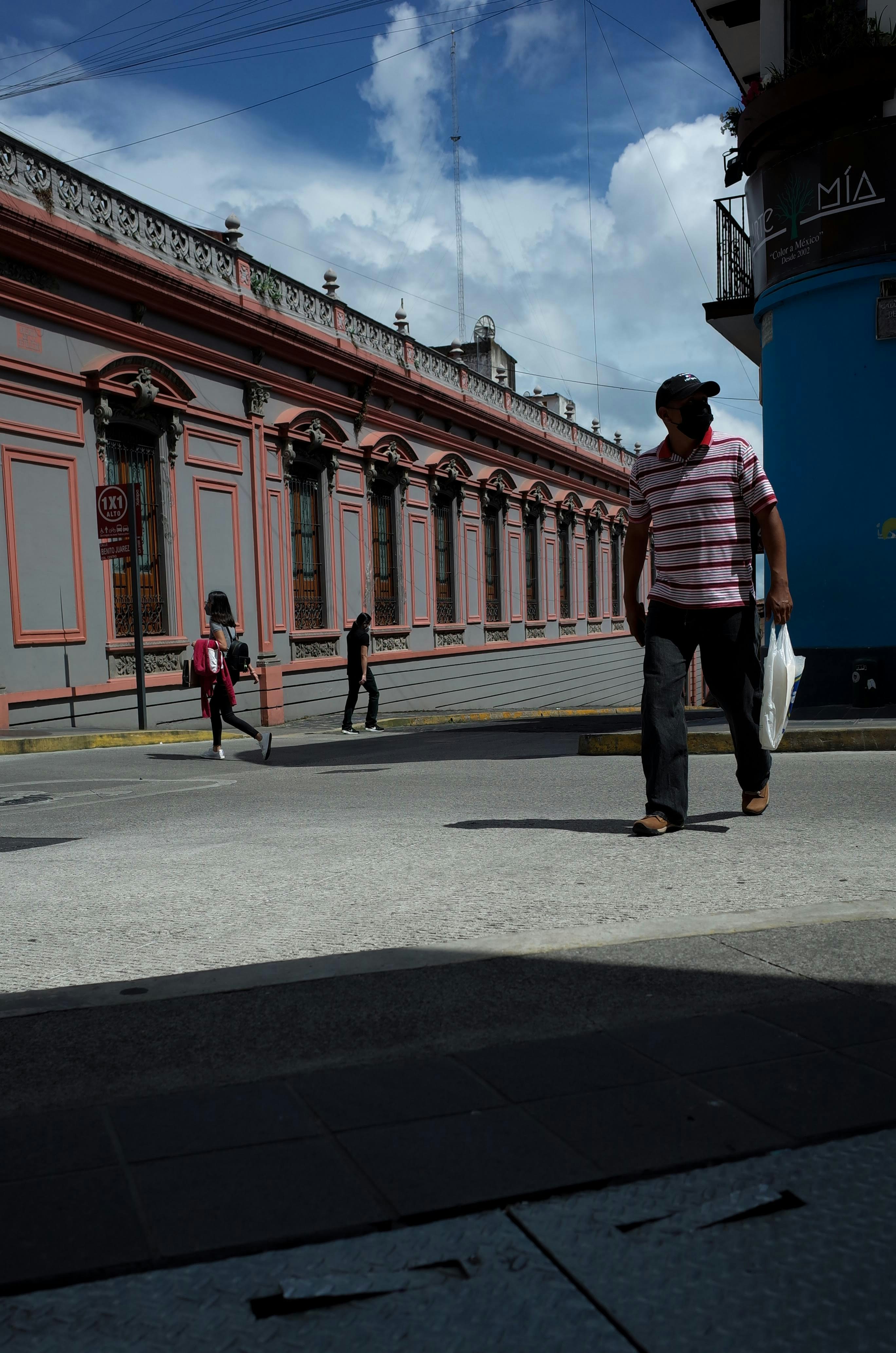 Ein Mann, der eine Straße neben einem hohen Gebäude entlanggeht