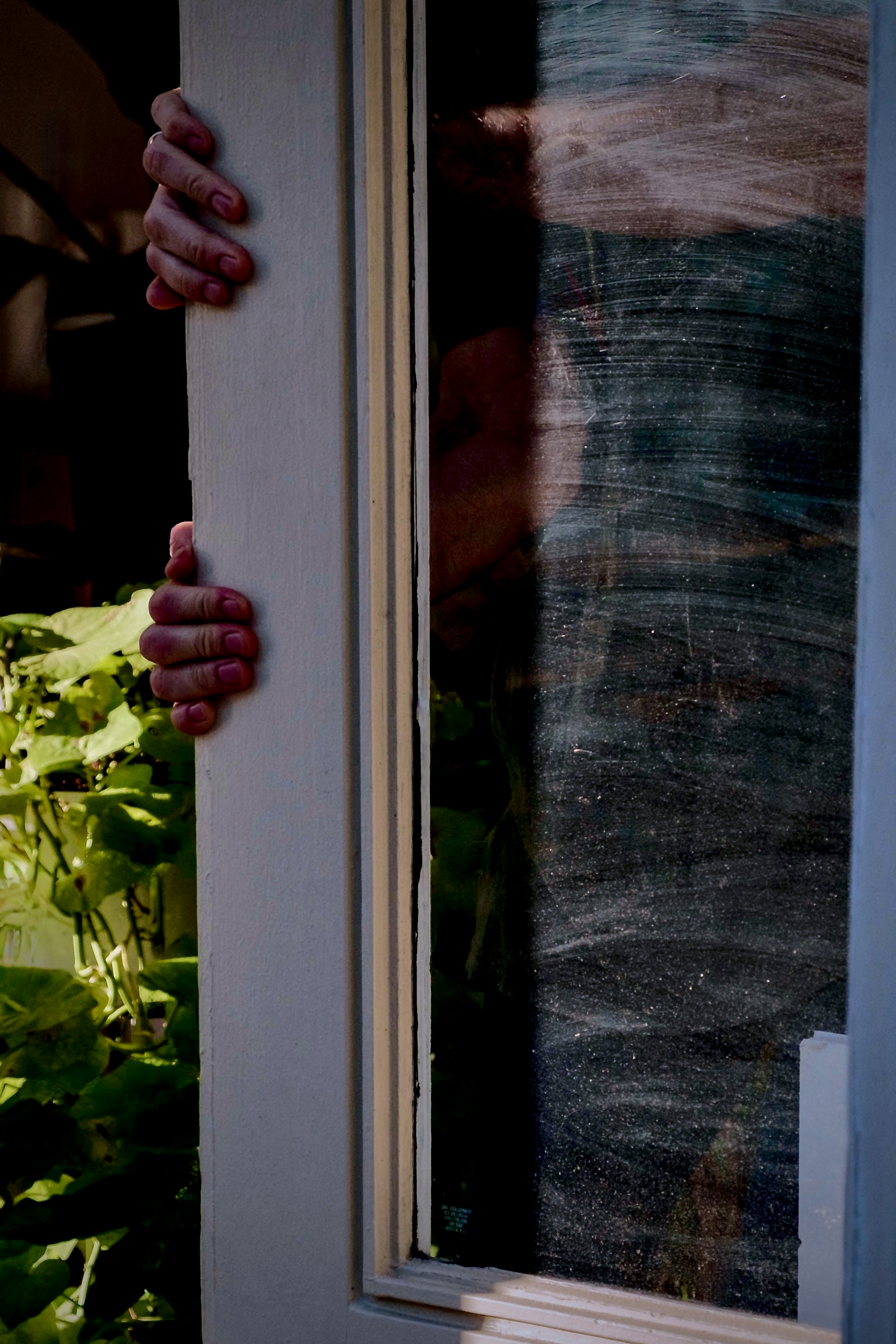 Die Hände einer Person, die sich an der Seite eines Fensters festhalten