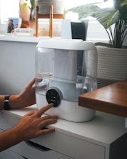 A person is holding a water dispenser on a counter