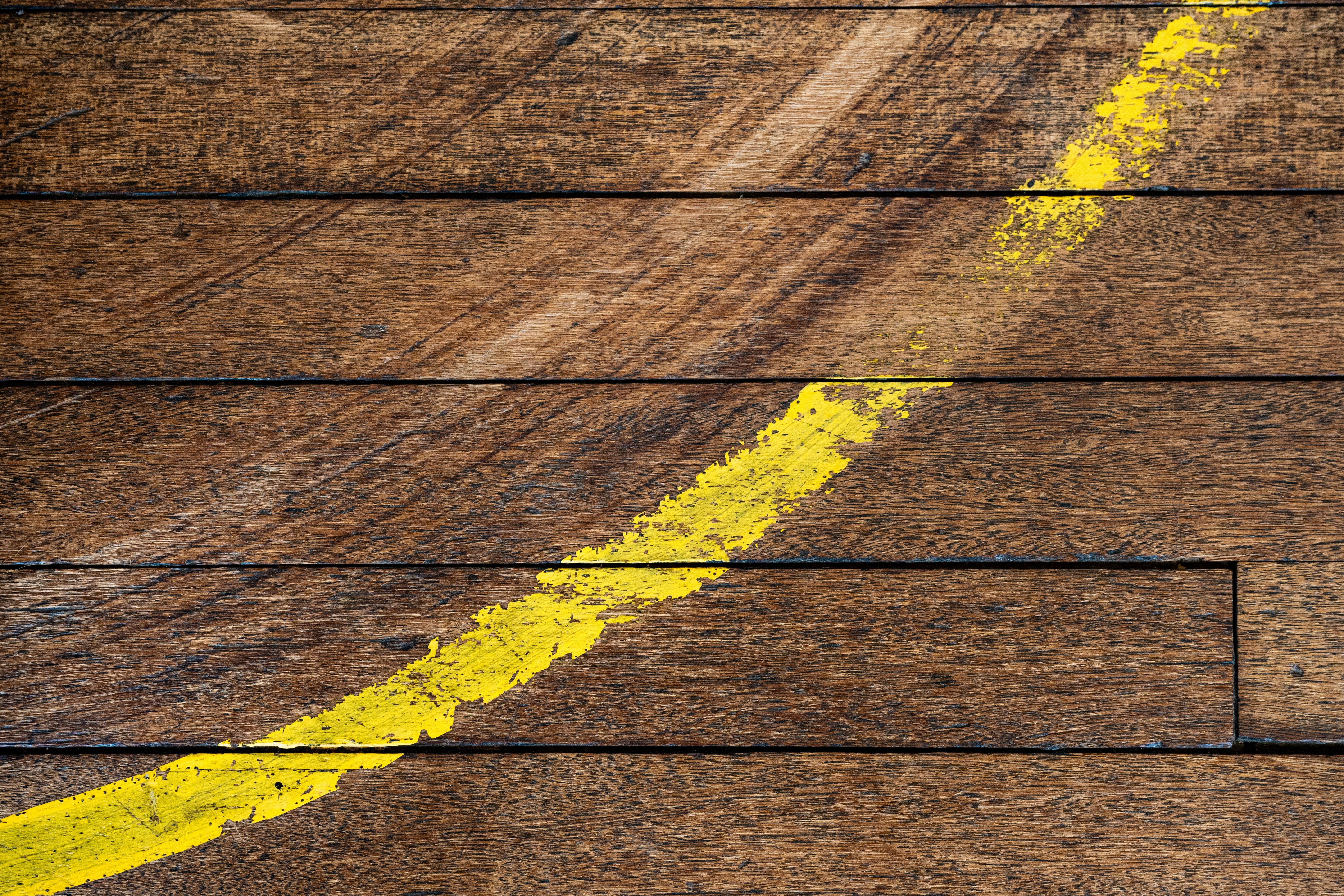 A wooden floor with a yellow line painted on it