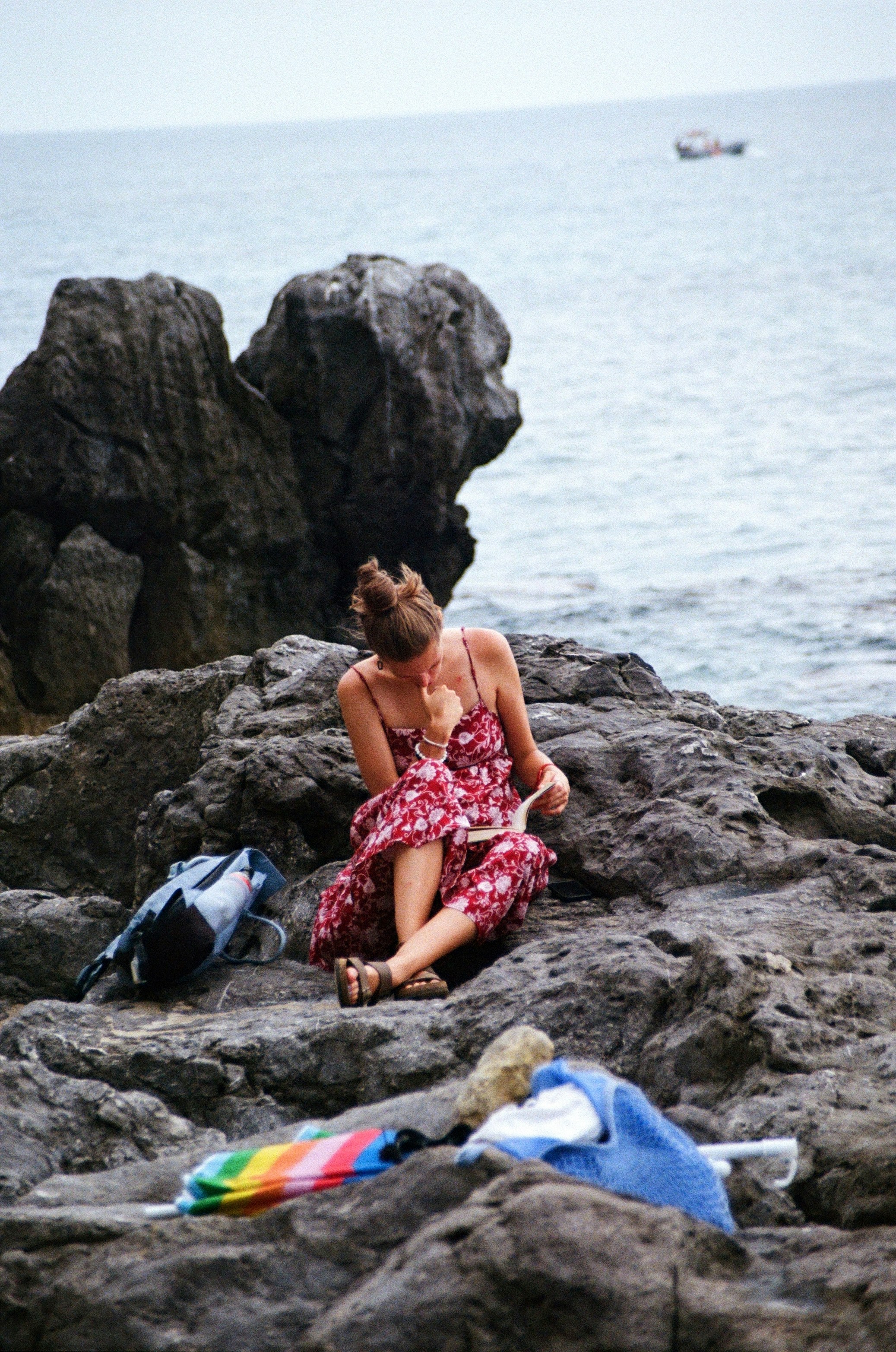 A woman sitting on a rock next to the ocean