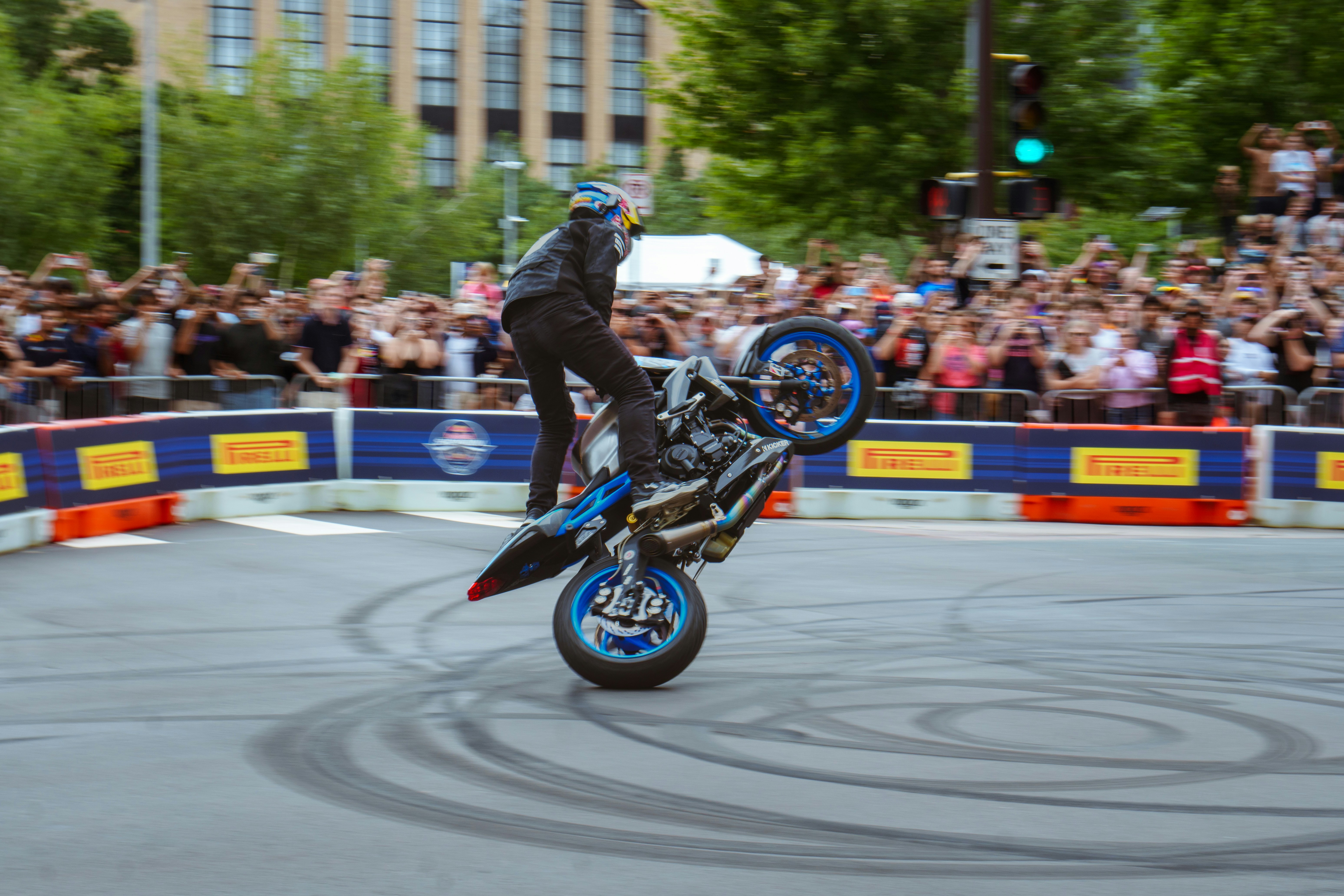A man on a motorcycle doing a trick in front of a crowd