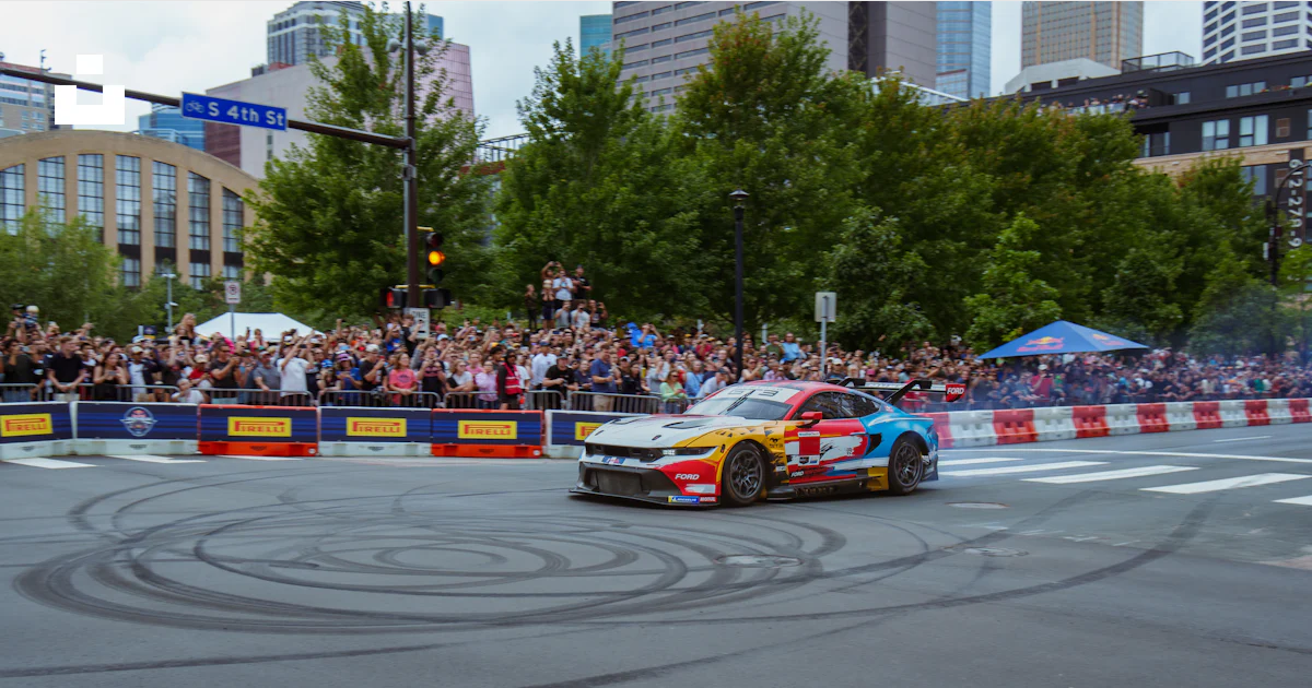 A car driving down a race track with a crowd watching photo – Free ...