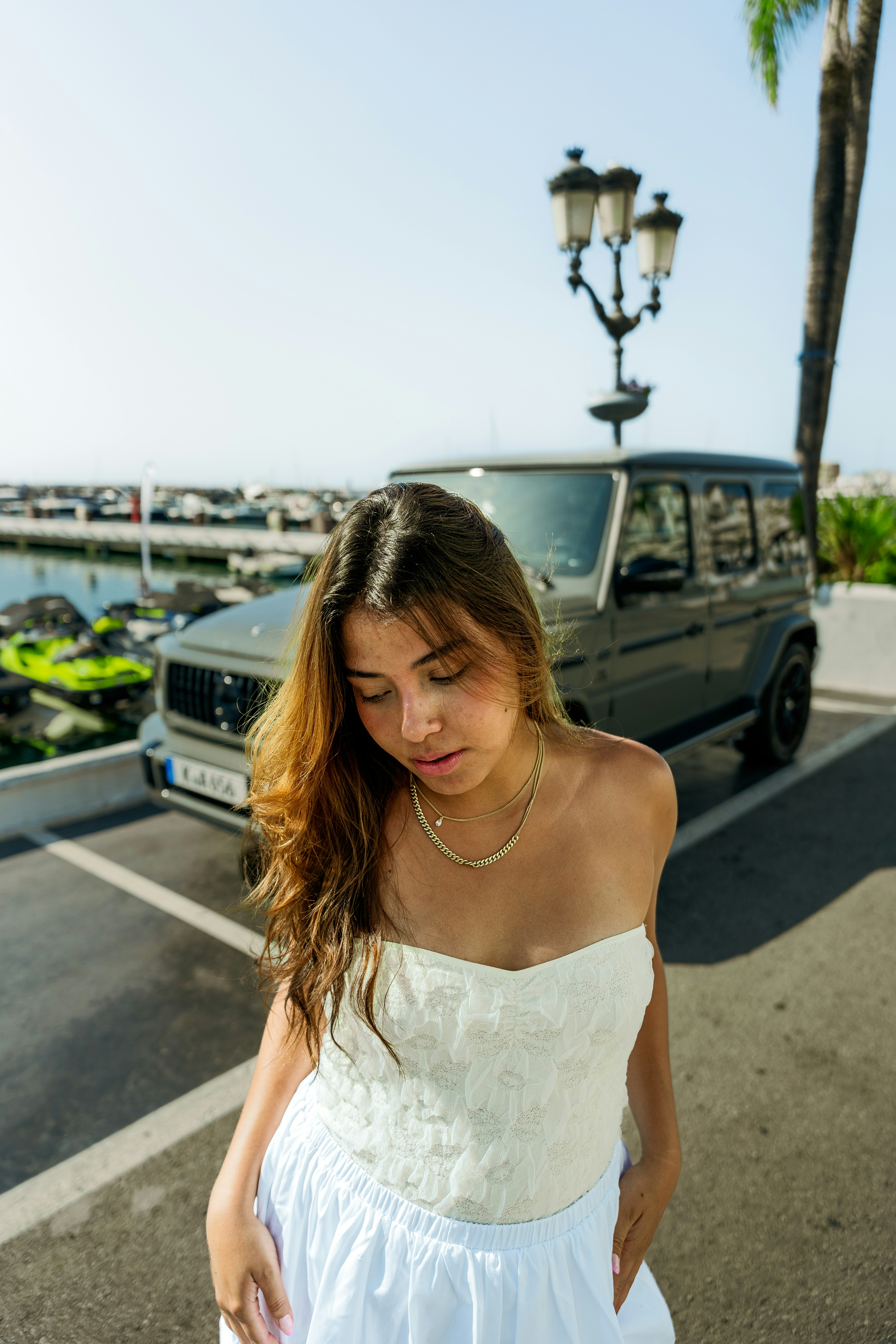 A woman in a white dress standing in front of a car