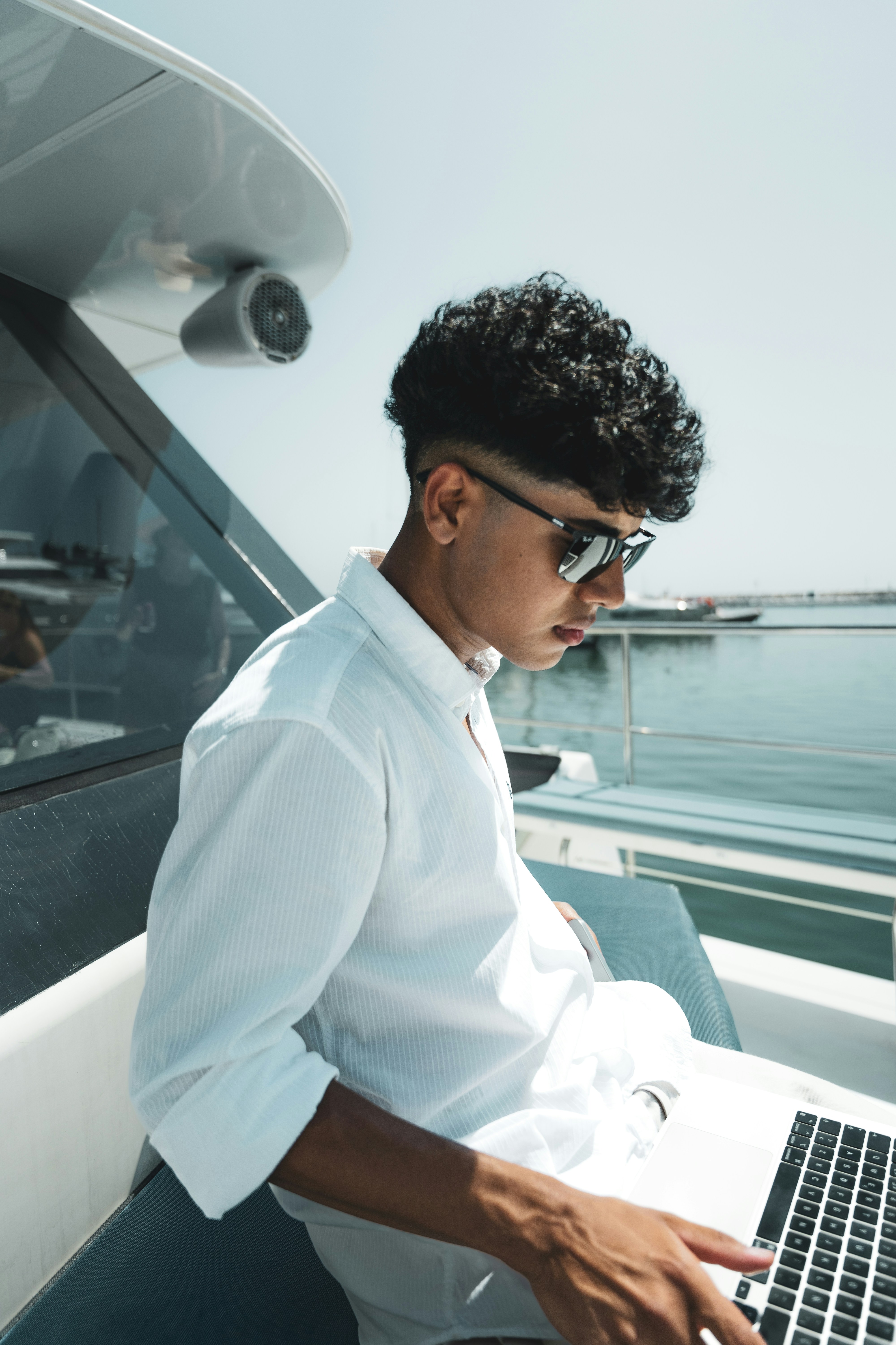 A man sitting on a boat using a laptop computer