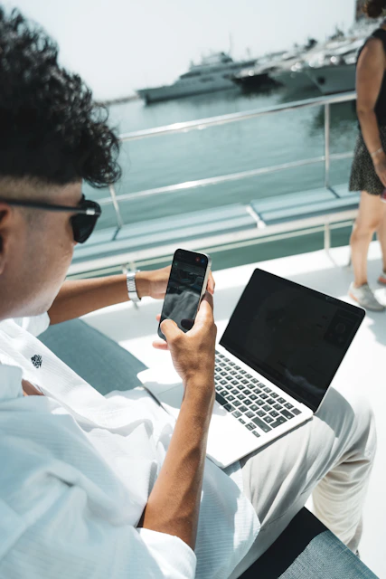 A man sitting on a boat using a cell phone