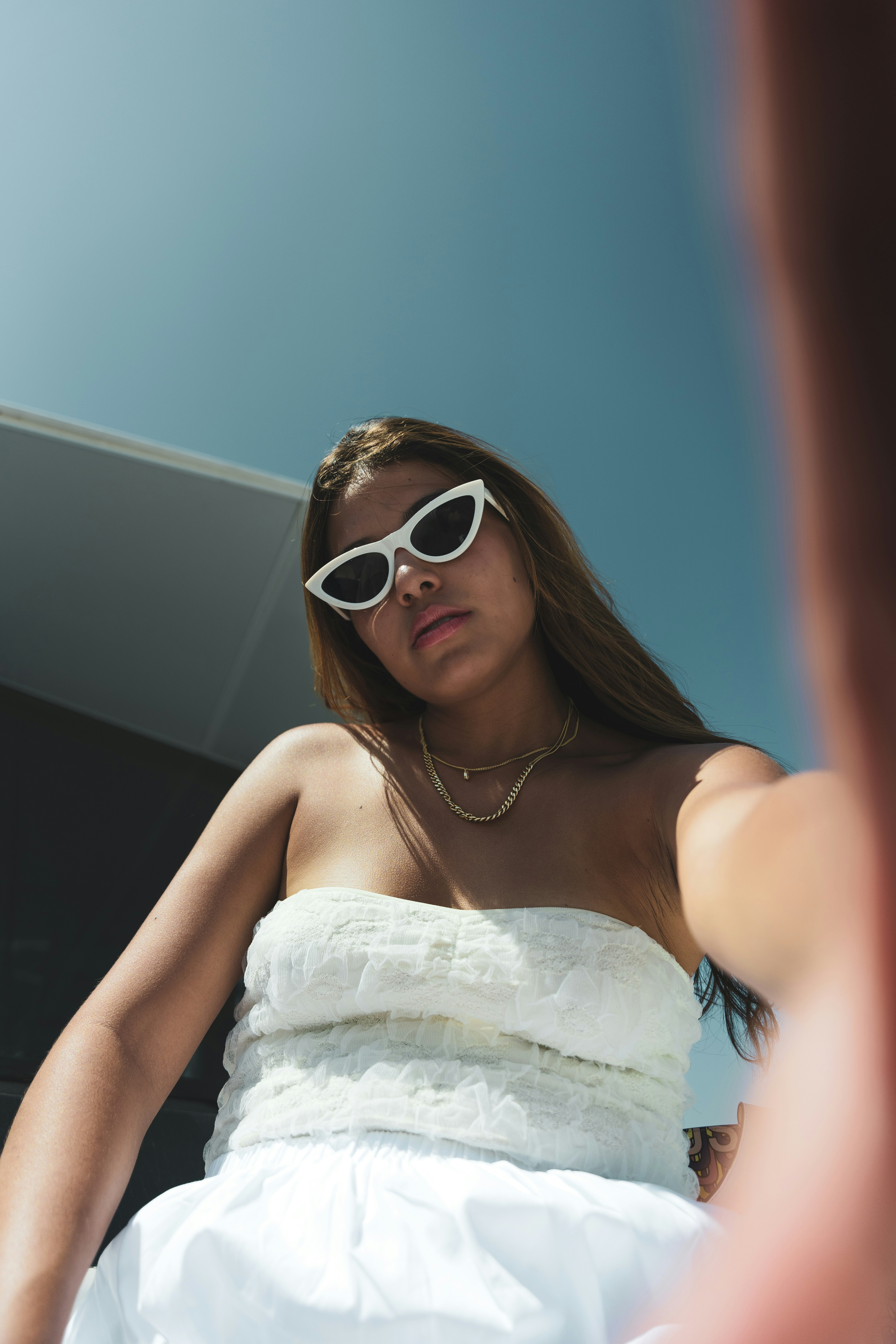 A woman in a white dress wearing sunglasses