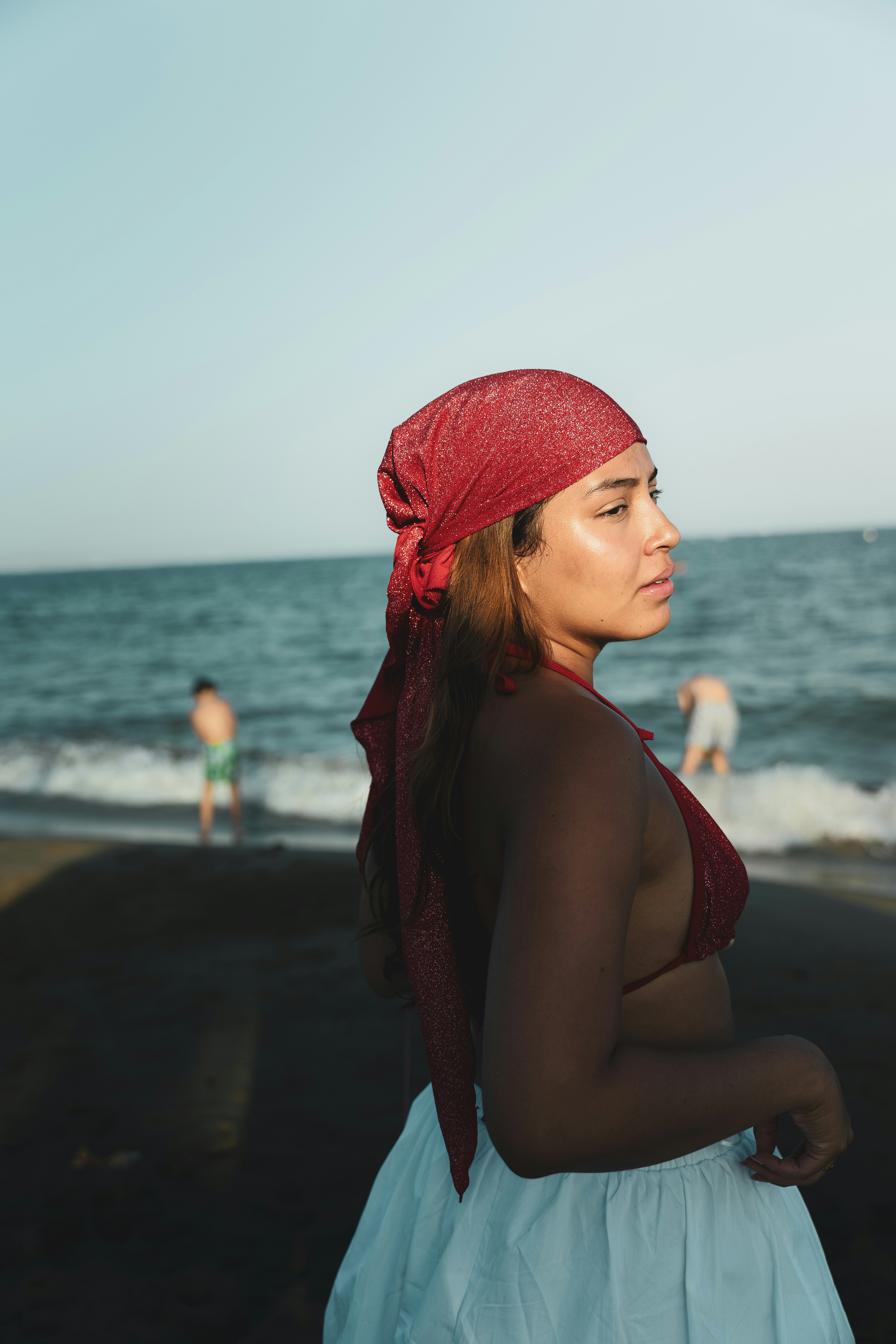 A woman wearing a red head scarf on the beach