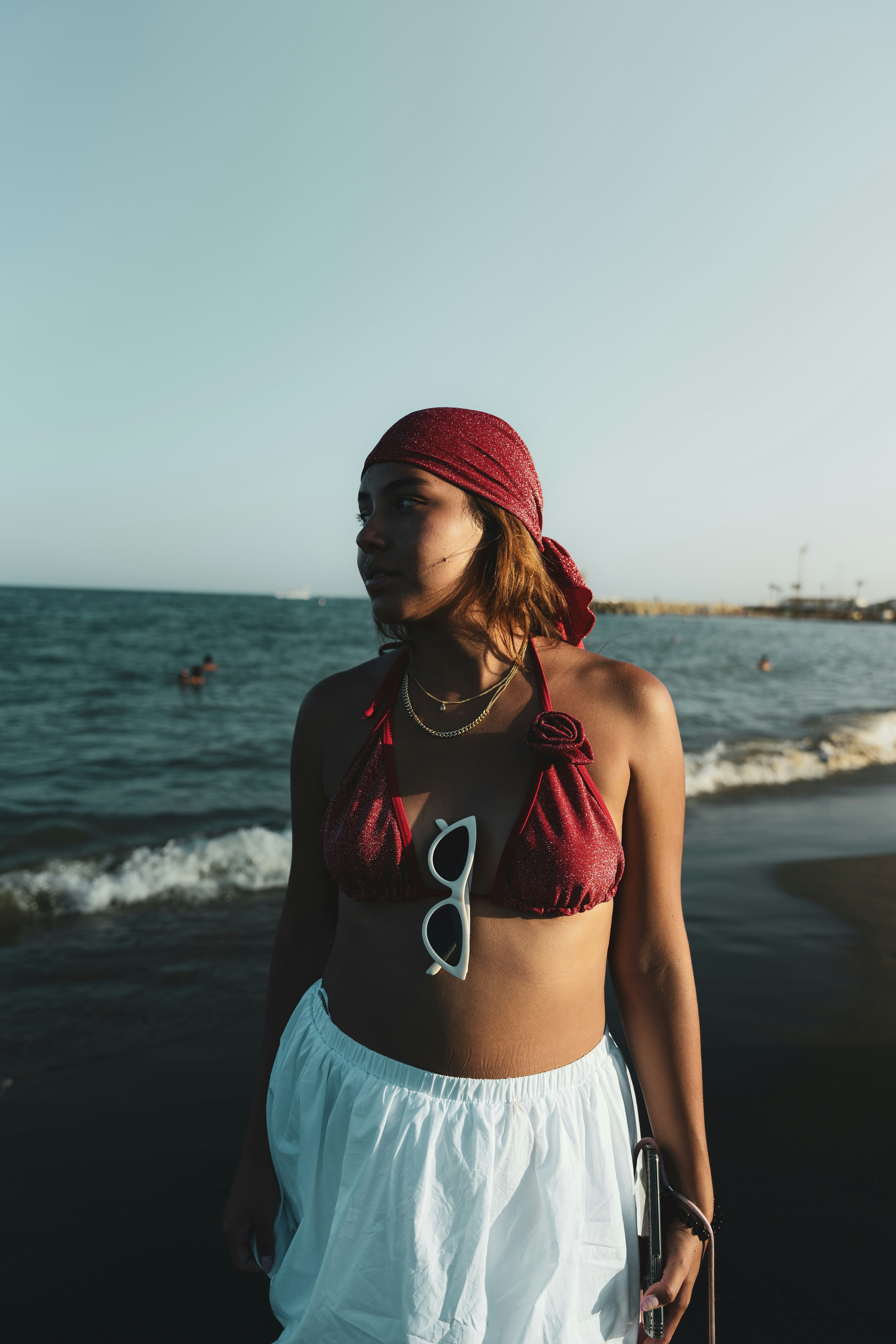 A woman standing on a beach wearing a white skirt