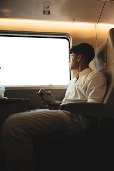 A man sitting on a train looking out the window