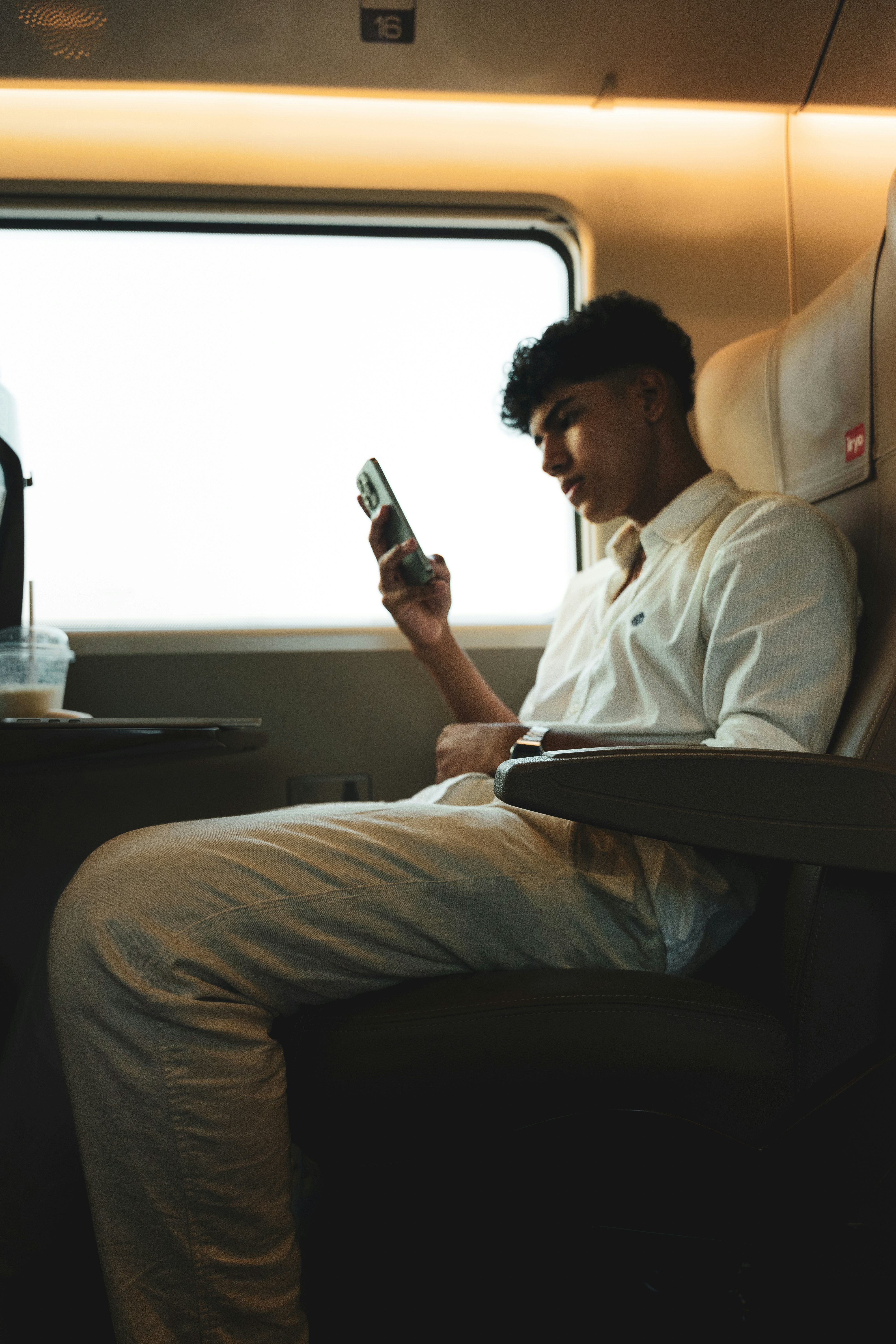A man sitting on a train looking at his cell phone photo Free