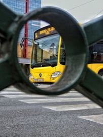 A view of a yellow bus through a pair of circular mirrors