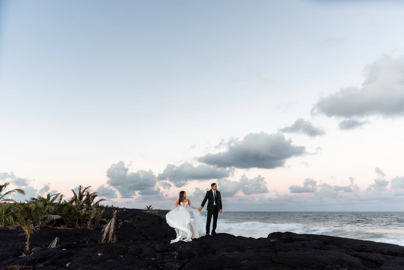 Couple during their elopement on Bartolomé Island in the Galápagos with the volcanic pinnacle and twin turquoise coves visible behind them