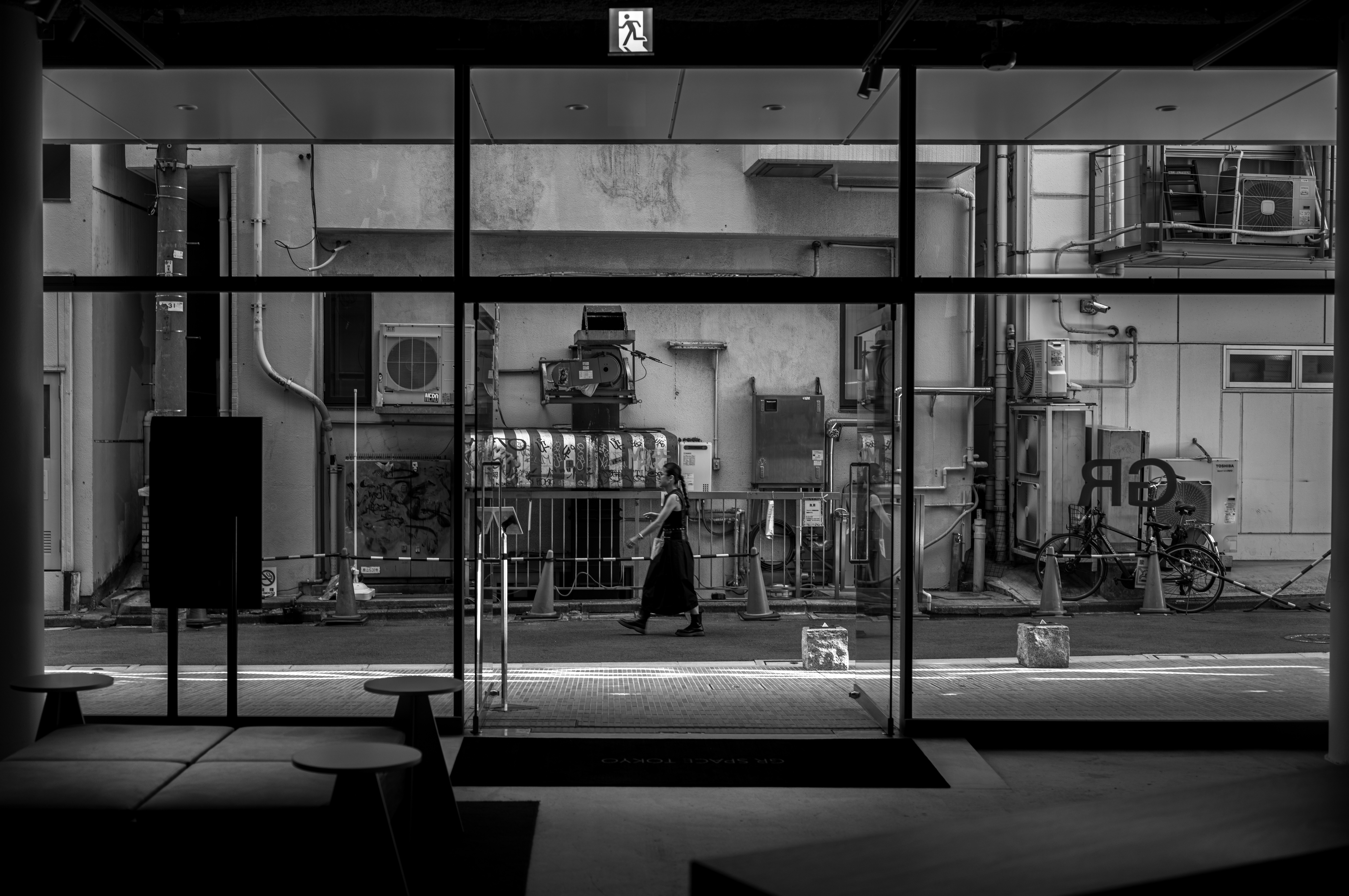 A black and white photo of a person walking in front of a building