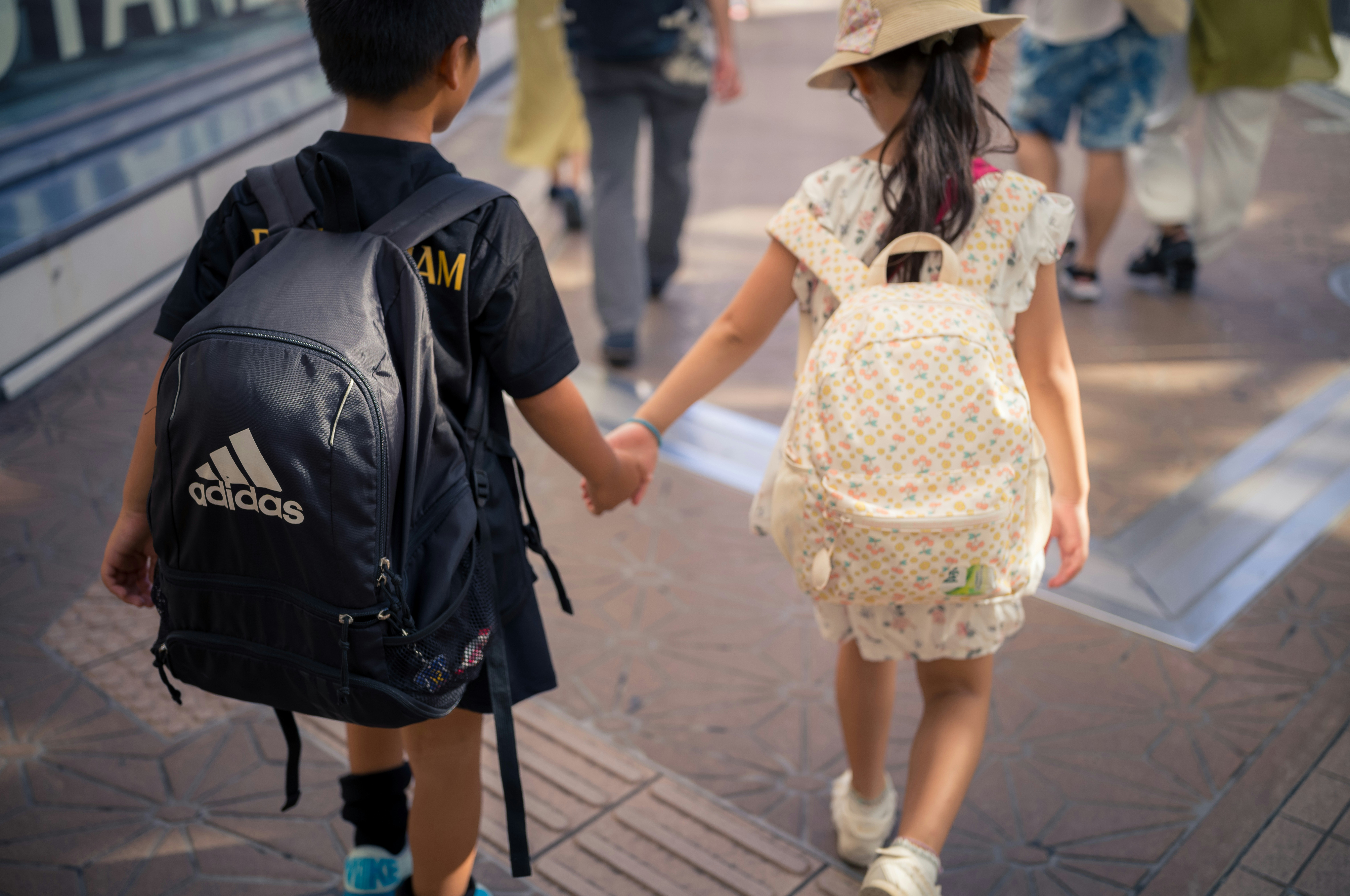 A couple of kids walking down a street holding hands