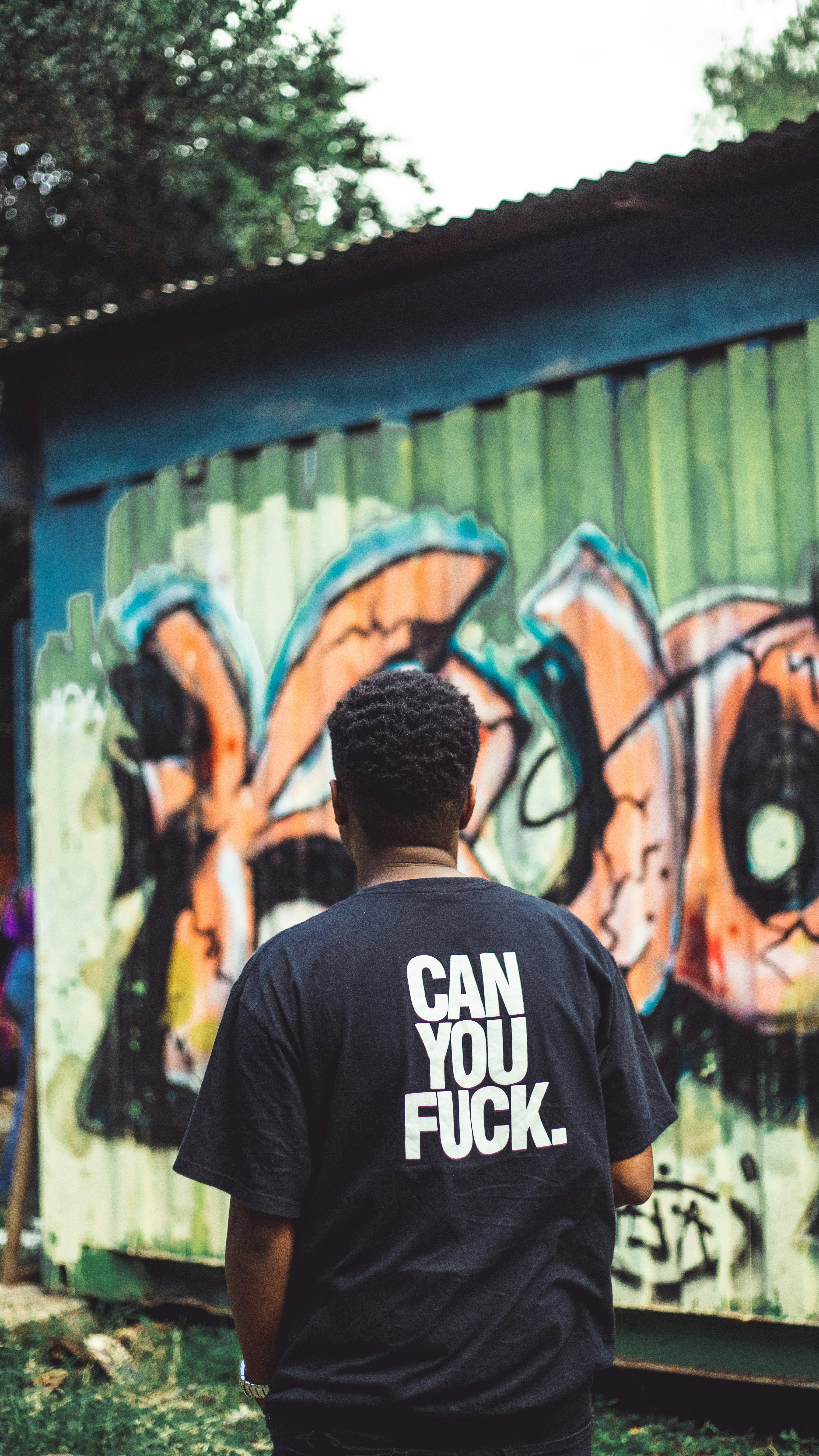 Um homem em pé na frente de uma parede coberta de grafite