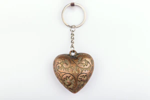 A metal heart shaped keychain hanging from a chain