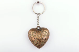 A metal heart shaped keychain hanging from a chain