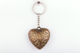 A metal heart shaped keychain hanging from a chain