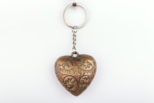 A metal heart shaped keychain hanging from a chain
