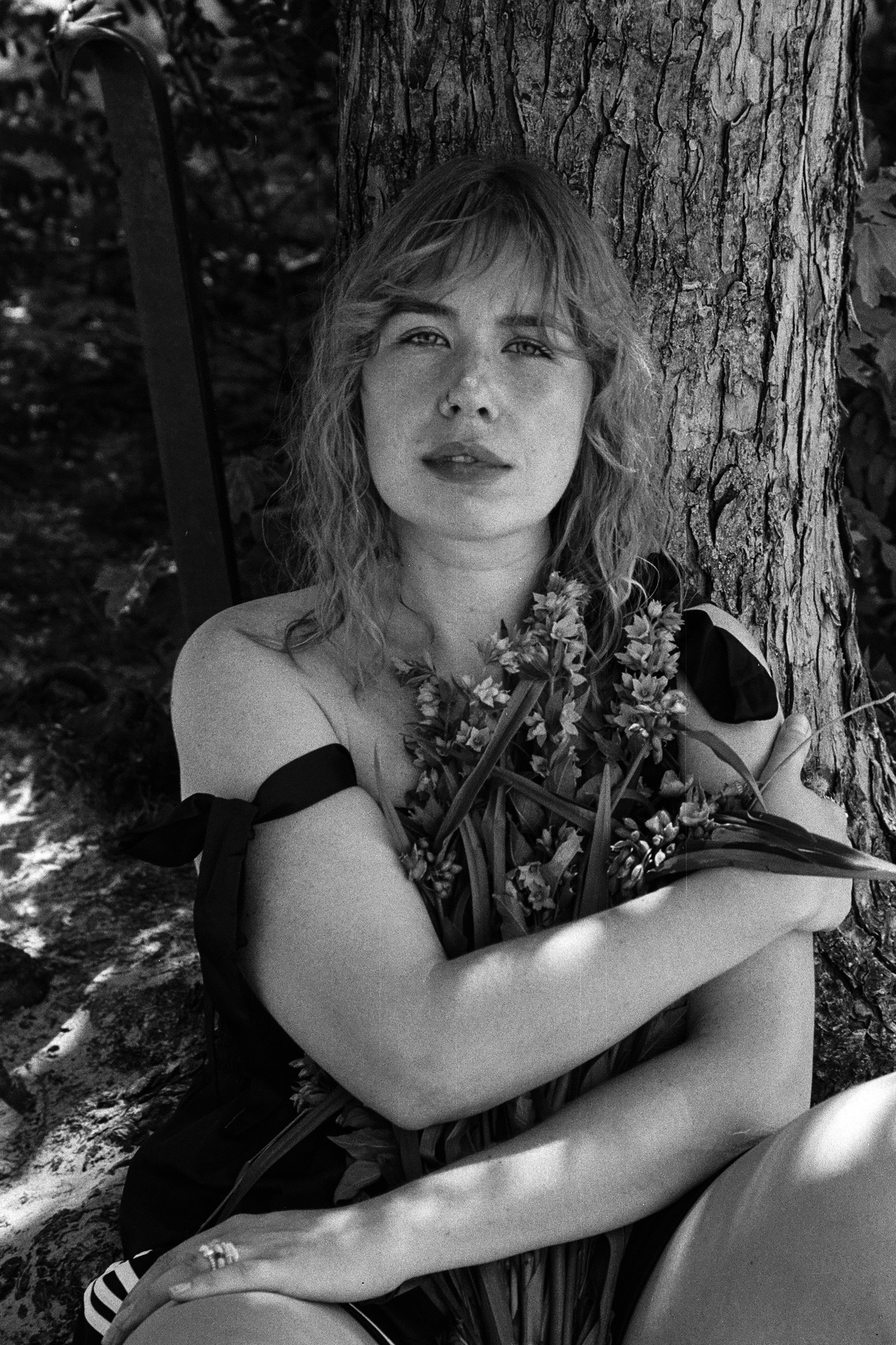 A woman sitting on the ground next to a tree