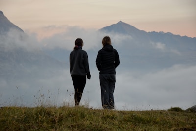 A couple of people standing on top of a grass covered hill