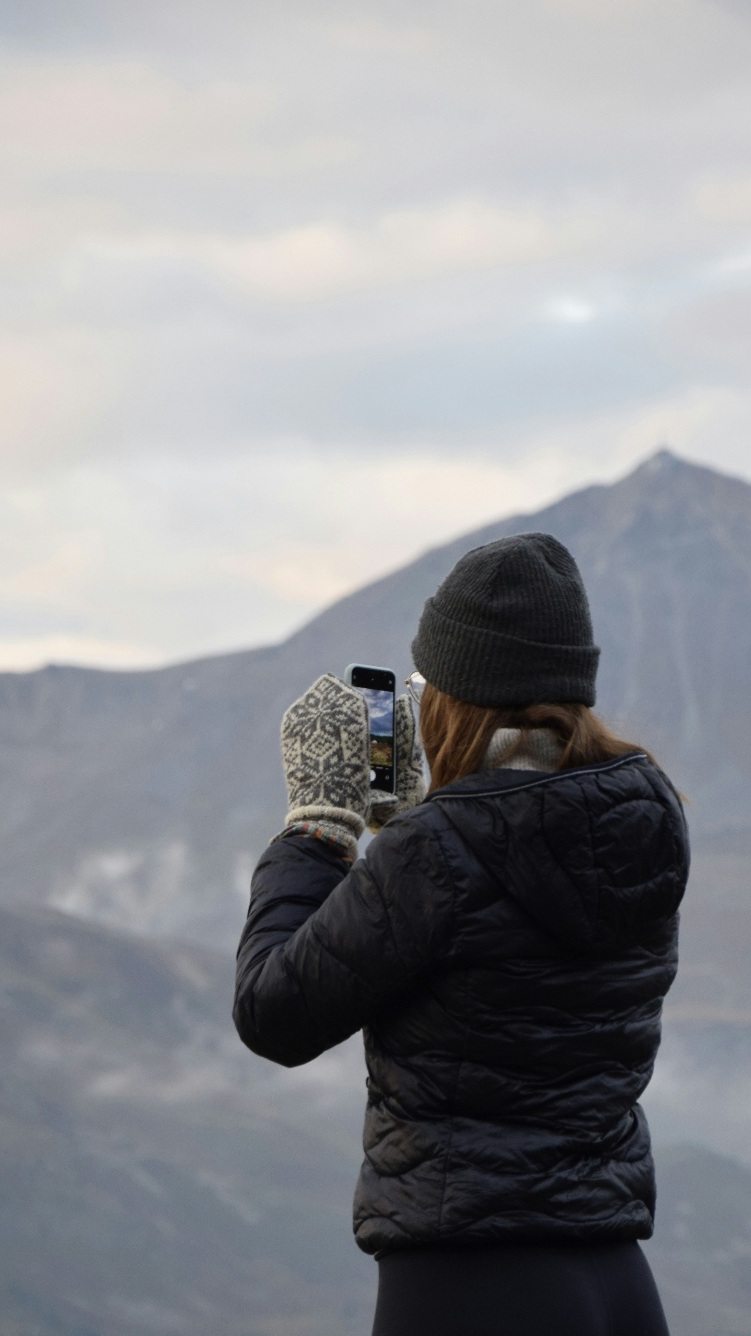 A woman taking a picture of a mountain