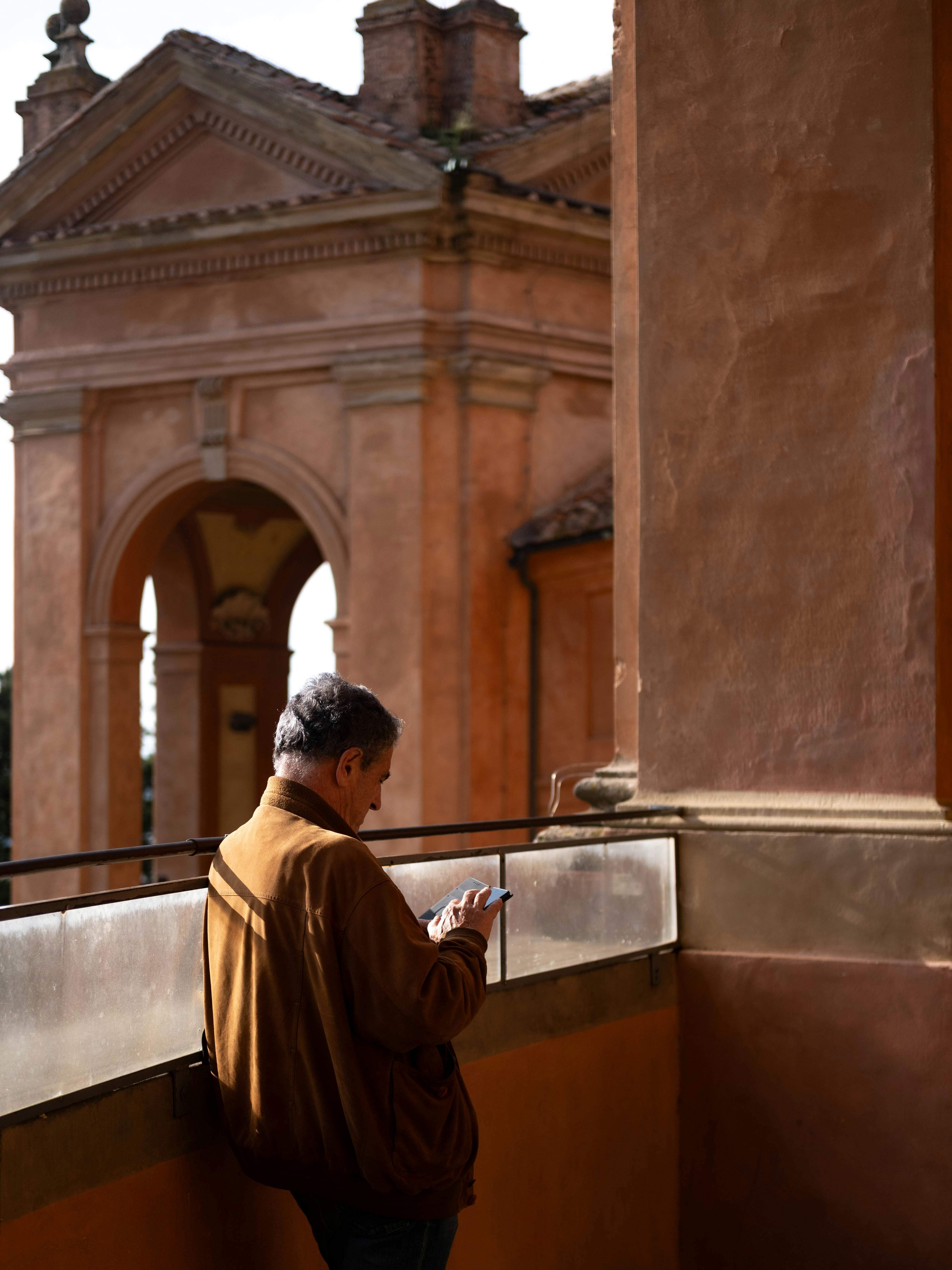 Un uomo in piedi su un balcone che guarda il suo cellulare