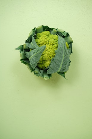 A head of broccoli sitting on top of a green wall