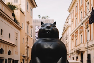 A statue of a cat sitting in the middle of a street