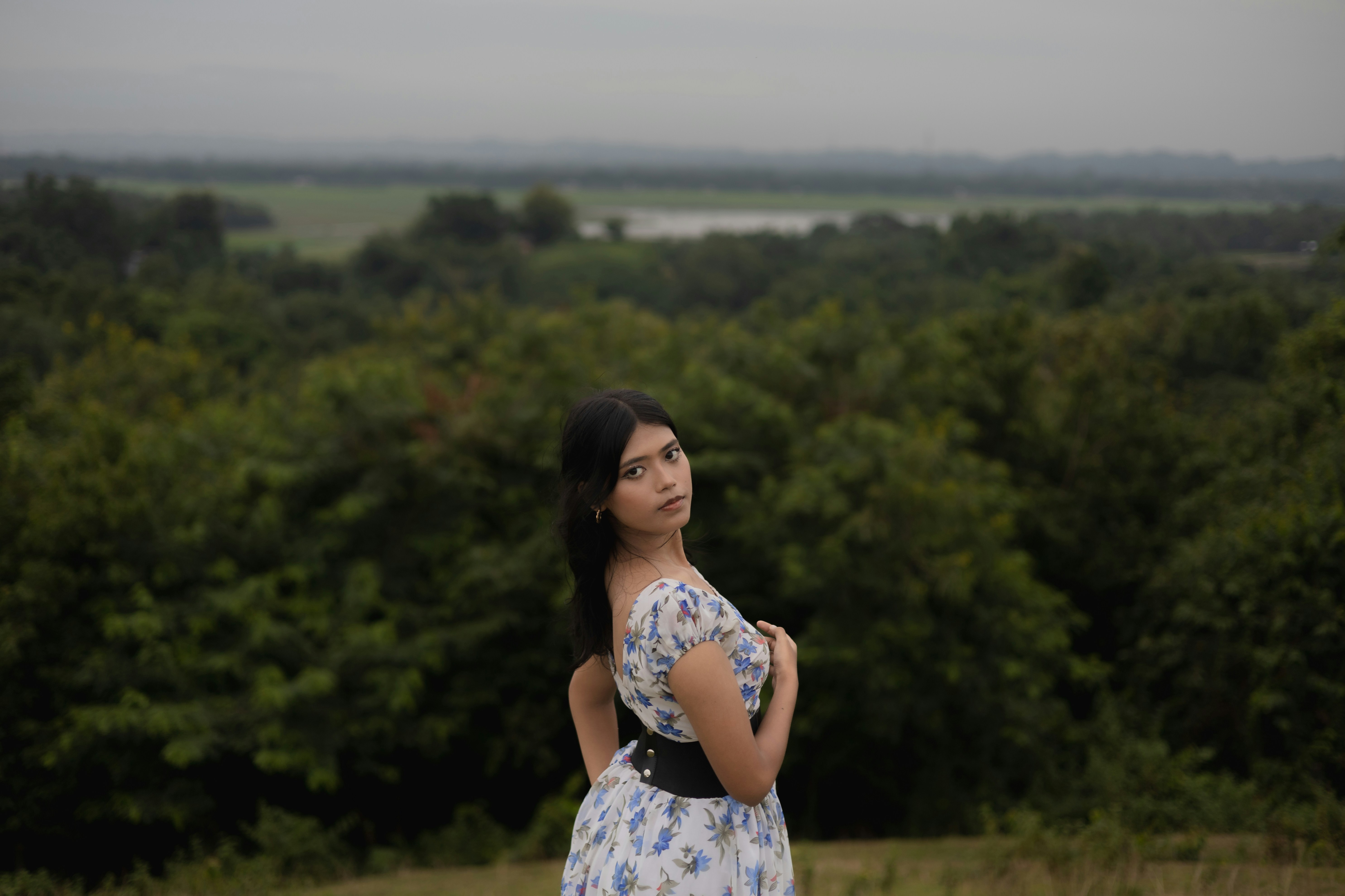 A woman standing in a field with trees in the background