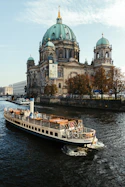 A boat traveling down a river in front of a large building