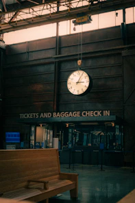 A large clock hanging from the ceiling of a building