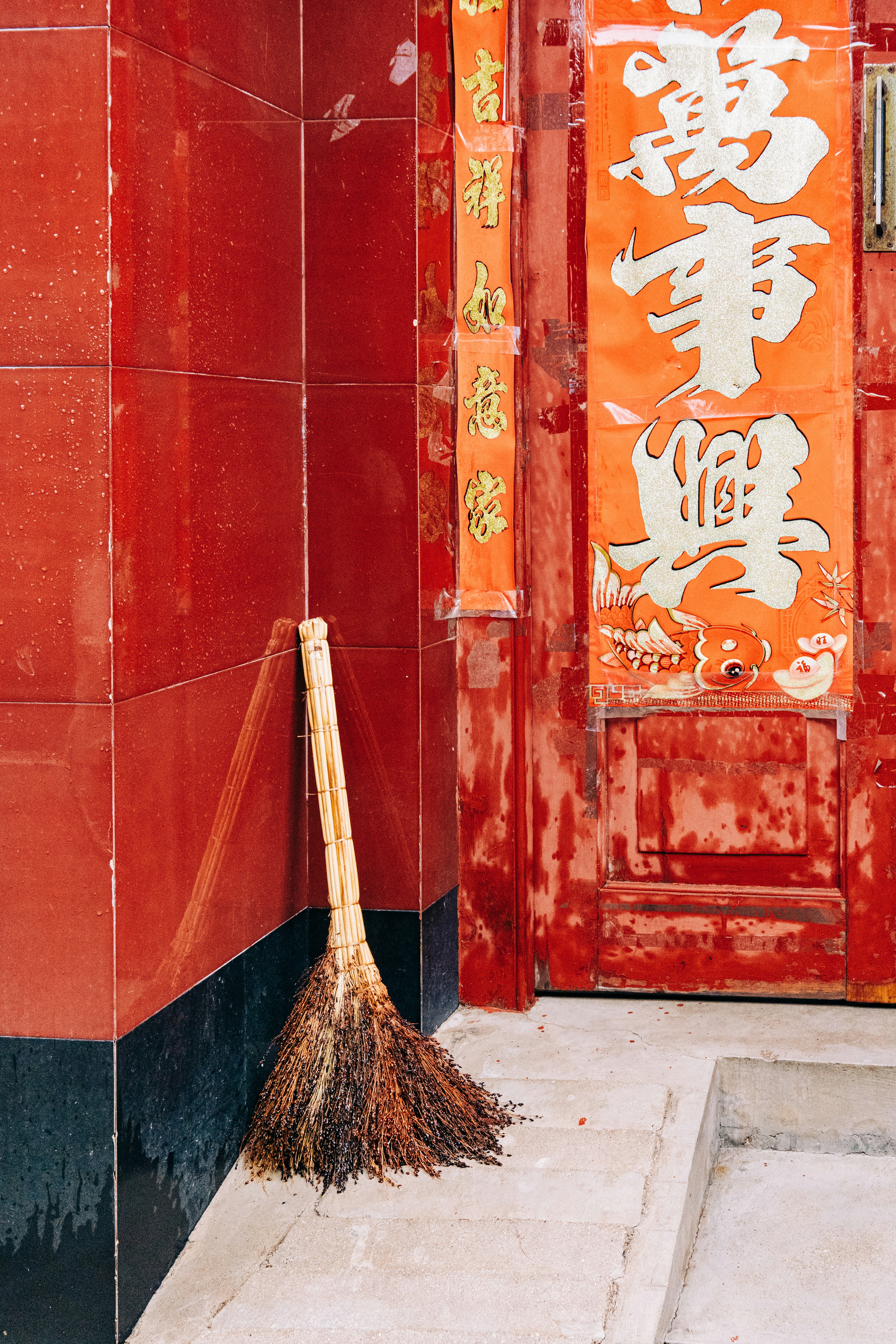 A broom sitting in front of a red door