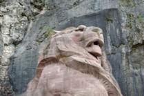 A statue of a lion in front of a rock face