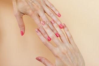 A woman's hands with pink manicures on them