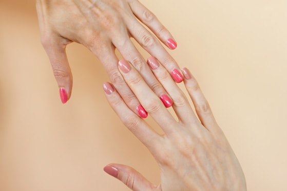 A woman's hands with pink manicures on them