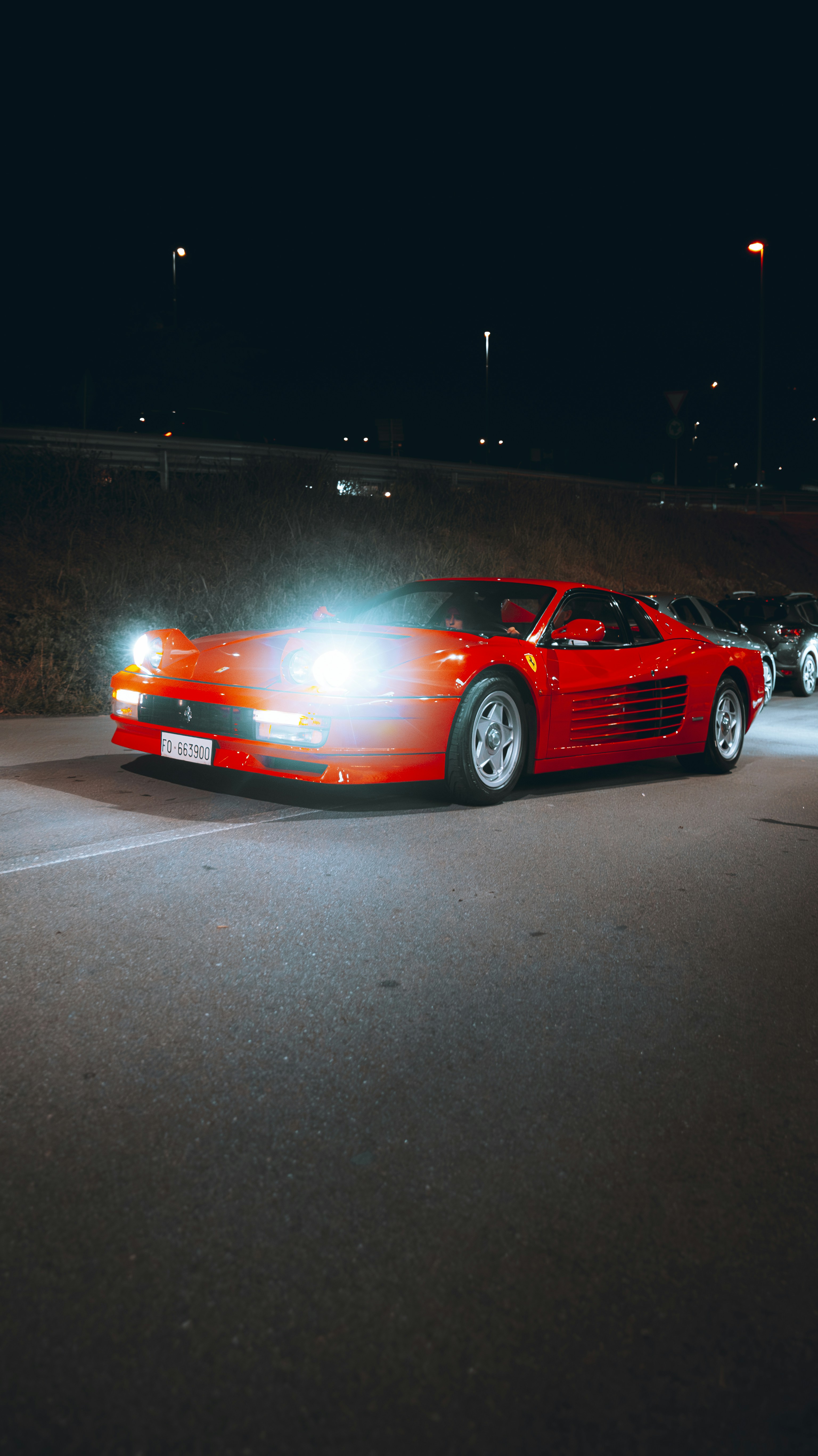 A red sports car parked in a parking lot at night