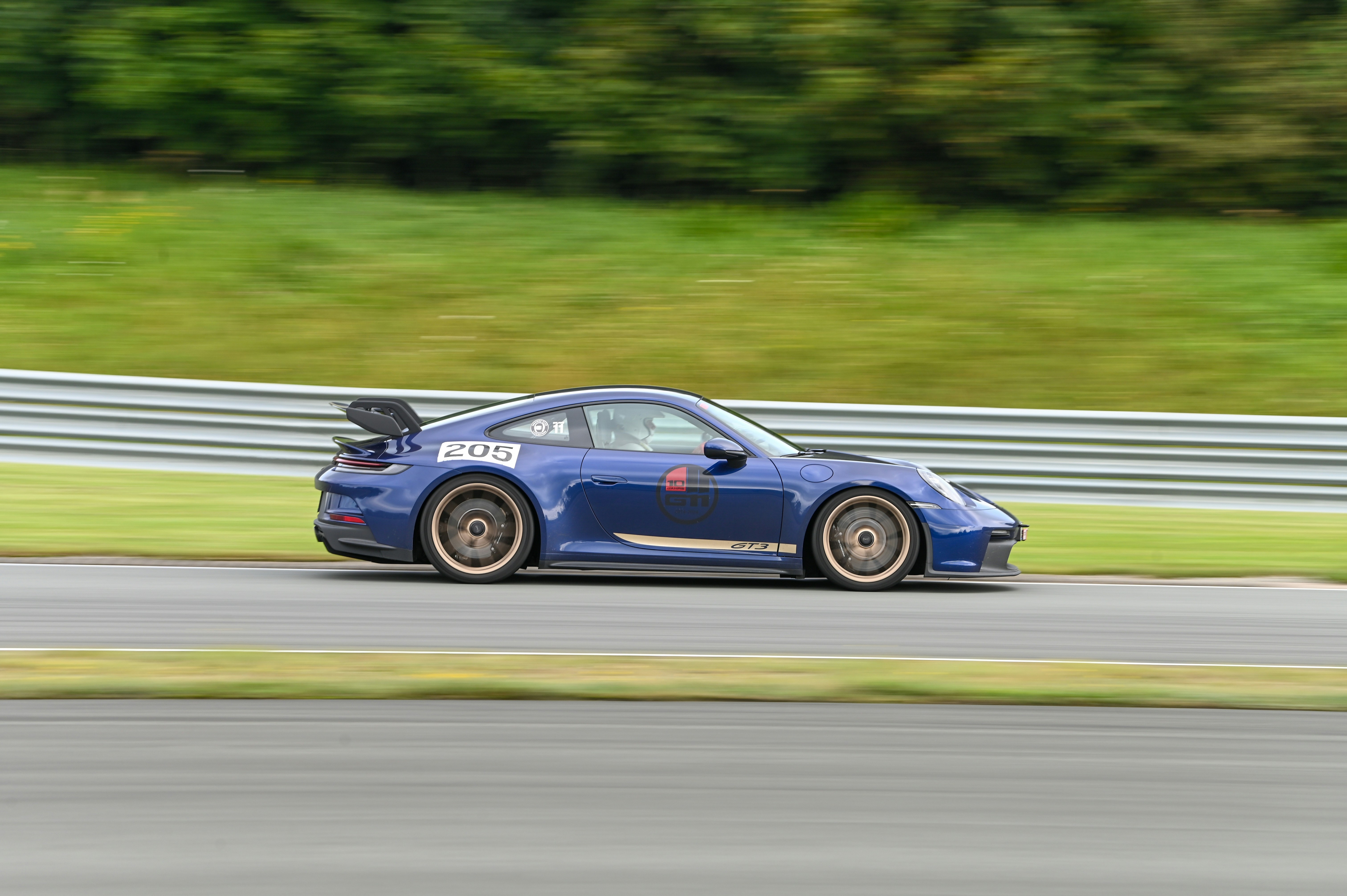 Silver Porsche 911 GT3 on race track, motion blur on wheels, overcast dramatic sky